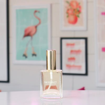 Clear glass perfume bottle with gold cap, labeled 'The Scarlett'. 