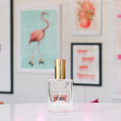 Clear glass perfume bottle with a gold cap, labeled 'The Antoinette'. 