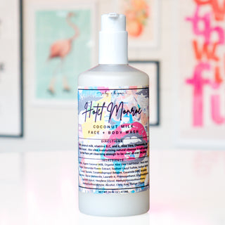A bottle of Ruby + Begonia Coconut Milk Face & Body Wash, featuring a white bottle and cap with a colorful label, set against a softly blurred background with pink flamingo artwork.