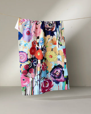 Colorful floral-patterned fabric hanging on a line against a plain background